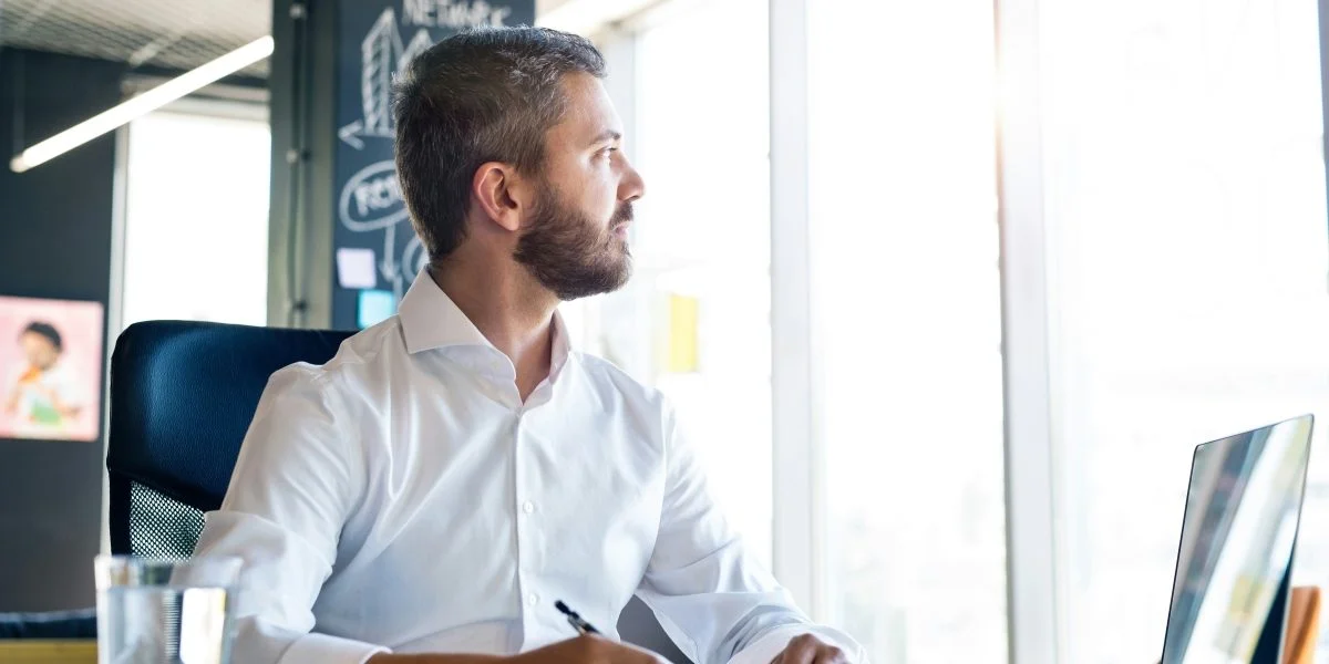 Entrepreneur working on business paperwork and compliance planning at a laptop in an office.