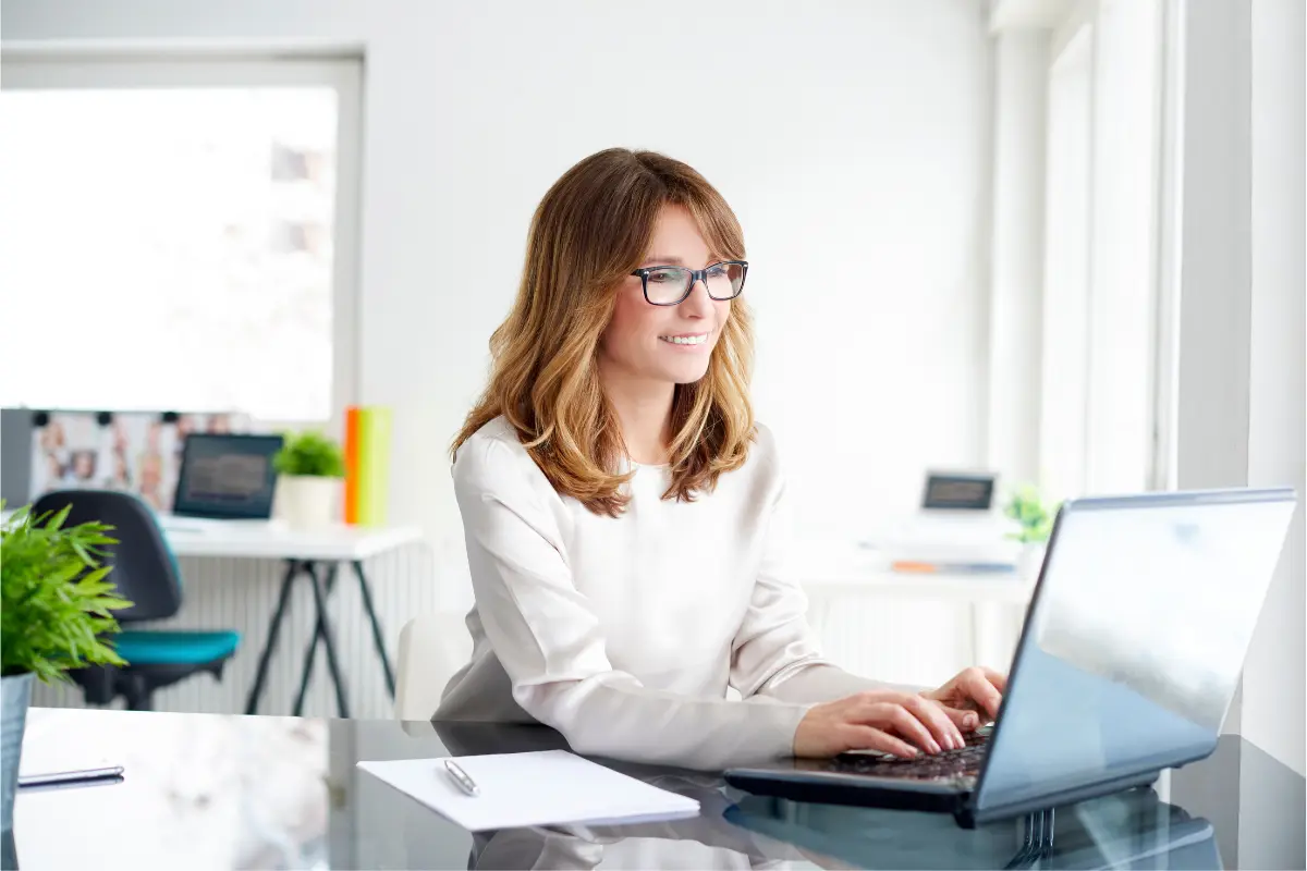 Professional businesswoman working on laptop in modern office managing registered agent services and business compliance requirements.
