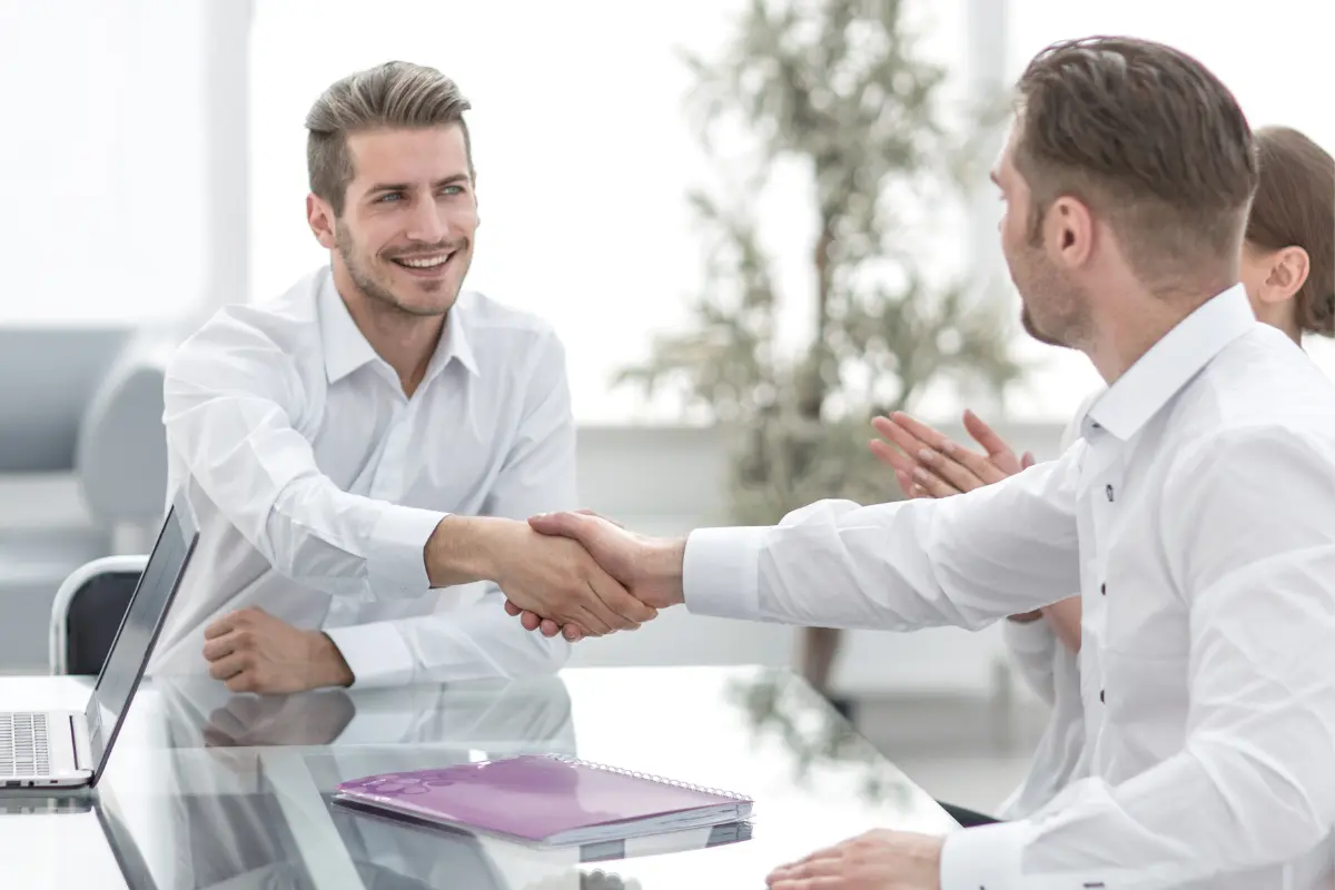 Two business professionals shaking hands after signing a business partnership agreement, symbolizing LLC partner removal or addition during partnership changes.