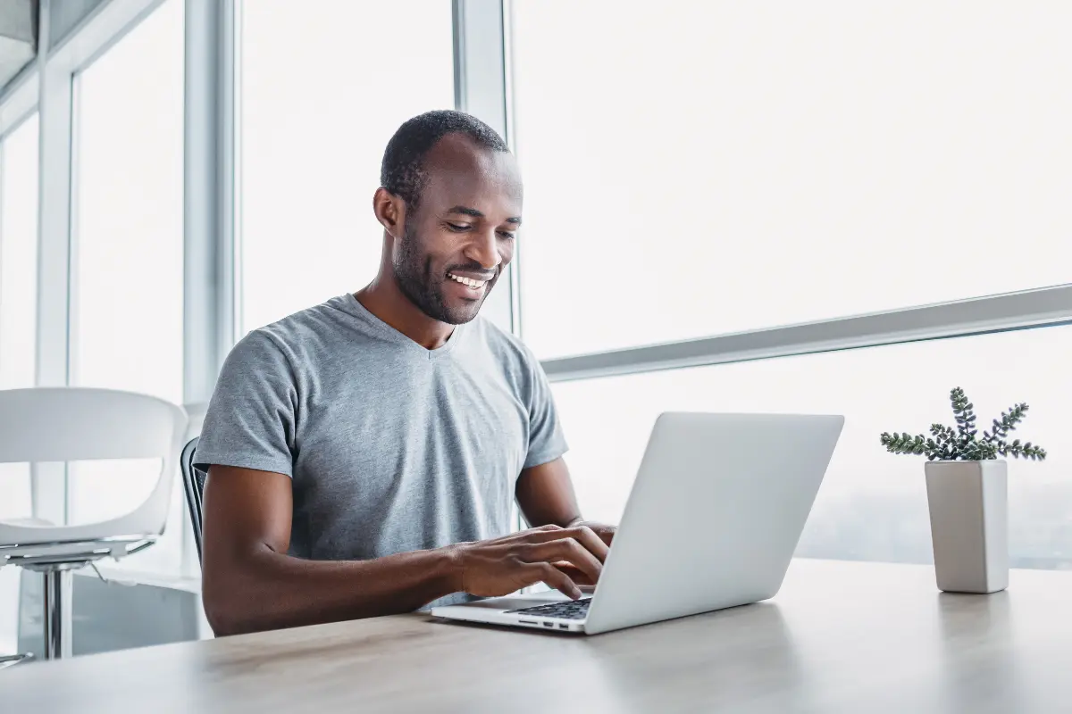 Smiling professional business owner working on laptop in modern office, symbolizing how to convert sole proprietorship to LLC.