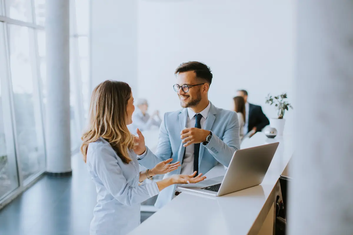 Two business professionals discussing how to start an ecommerce business plan at a modern office desk with a laptop