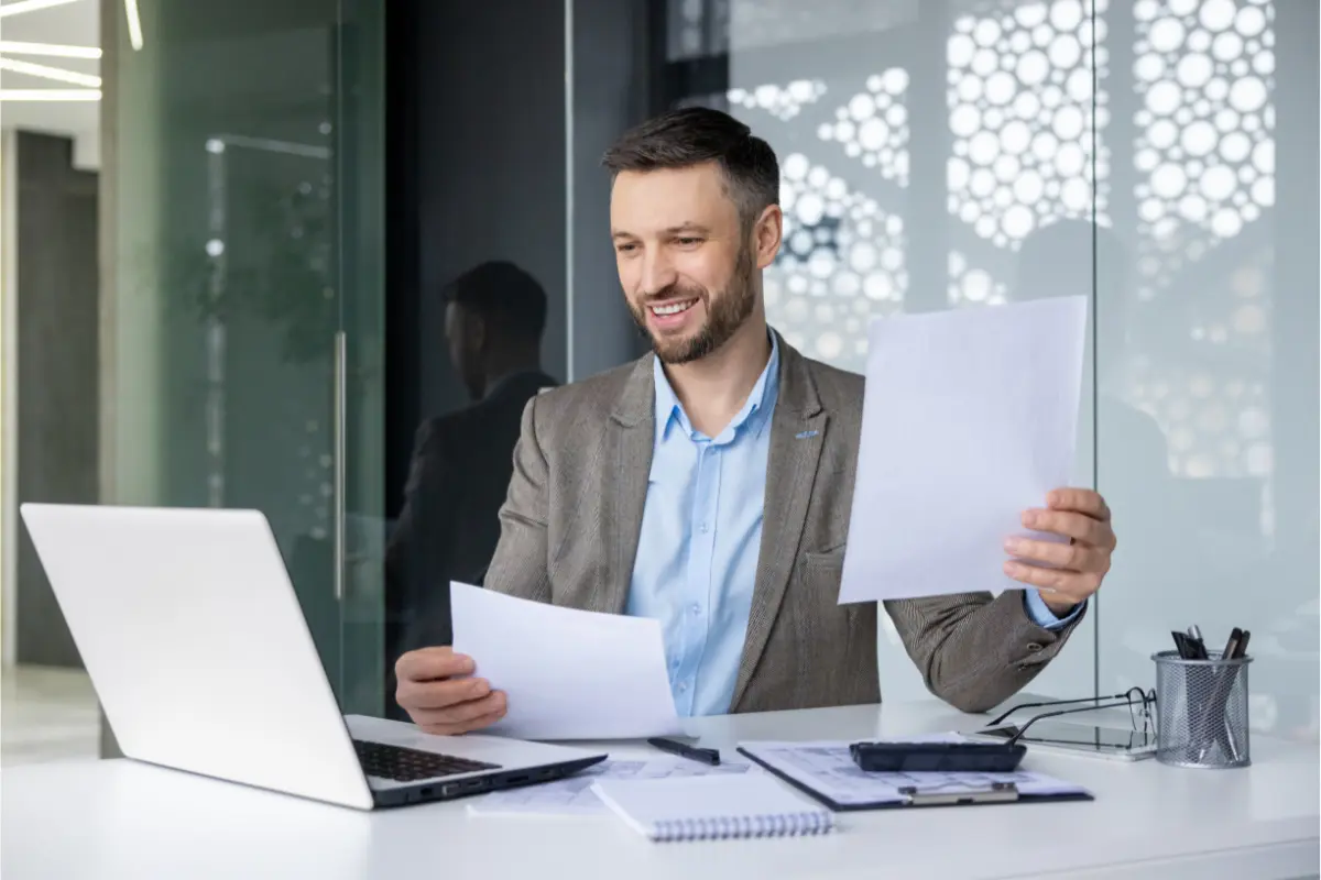 Business owner reviewing LLC formation service documents and cost breakdown at office desk with laptop