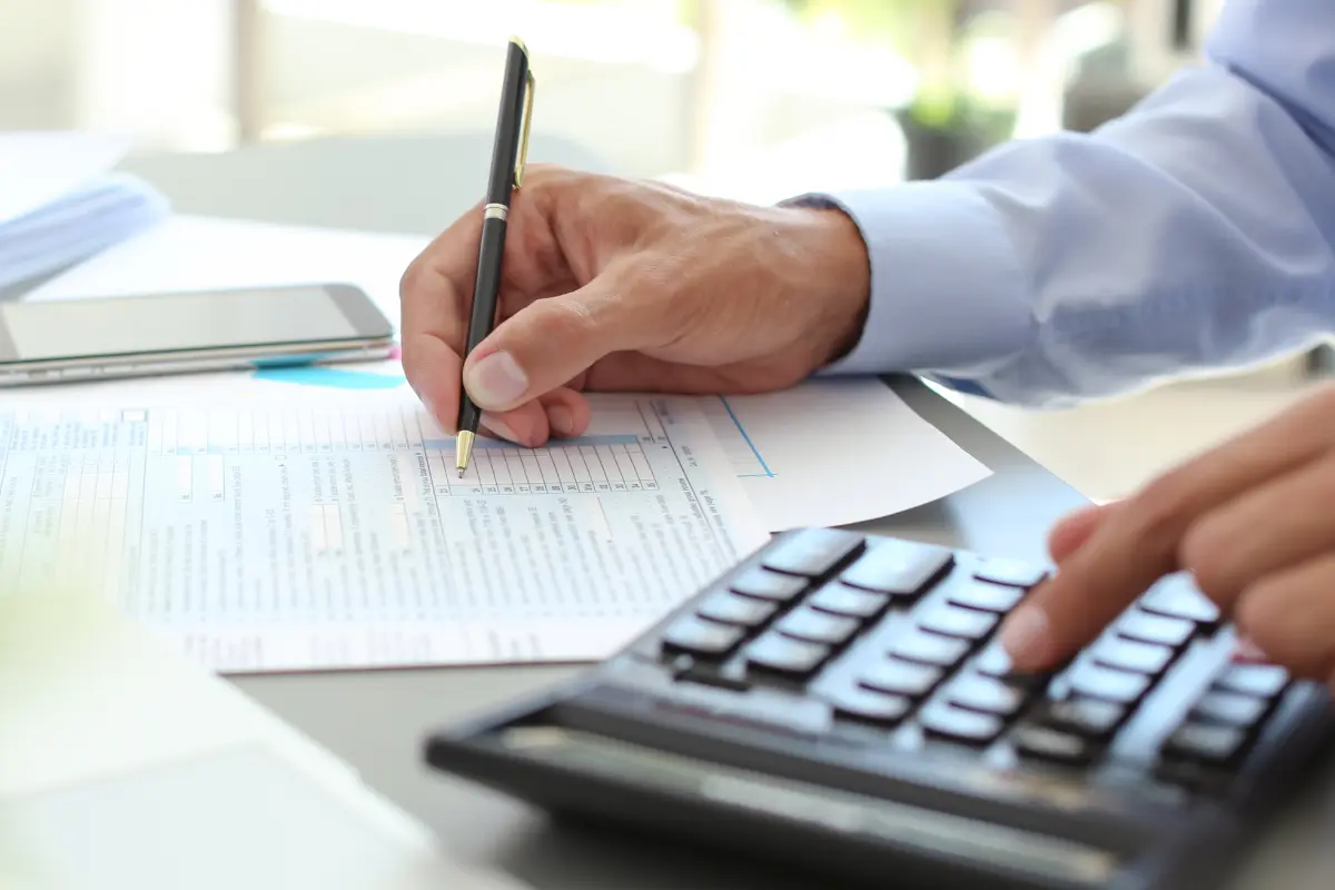 LLC owner calculating business expense deductions and IRS deductions for 2026 using a calculator and tax forms to maximize deductible business expenses and reduce taxable income