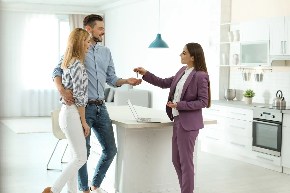 Real estate agent handing keys to new property owners representing the importance of a real estate LLC structure with professional registered agent services to protect personal assets and maintain business compliance