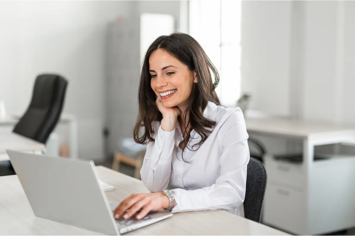 Smiling service-based business owner managing LLC registration and legal structure requirements on laptop at office desk